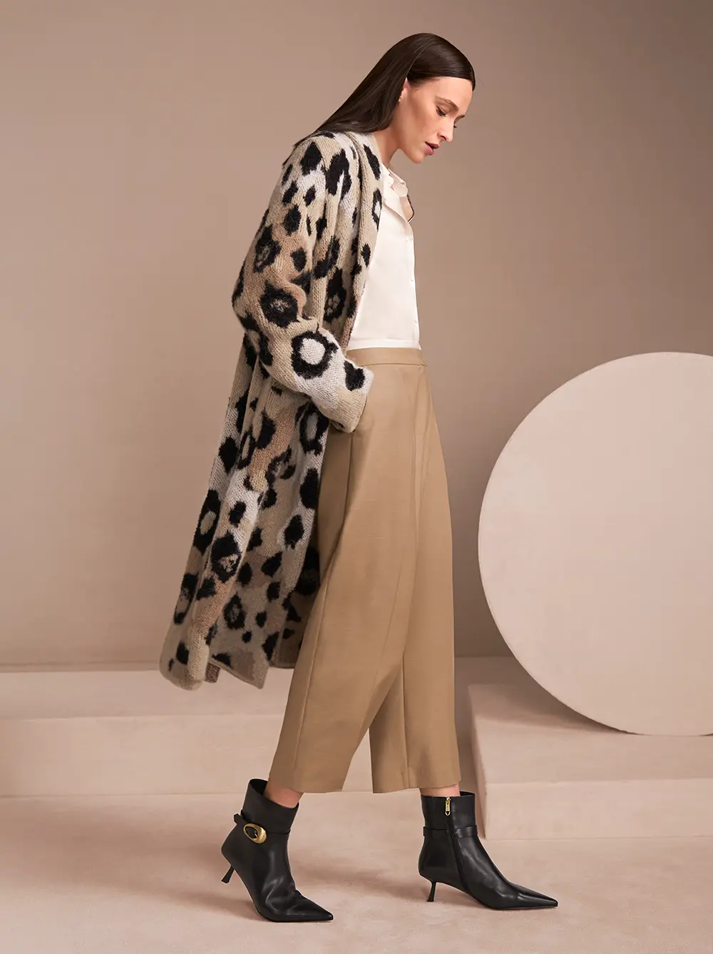 Gestrickter, langer Mantel mit großflächigem Leoprint, weißer Bluse und hellbrauner Hose
